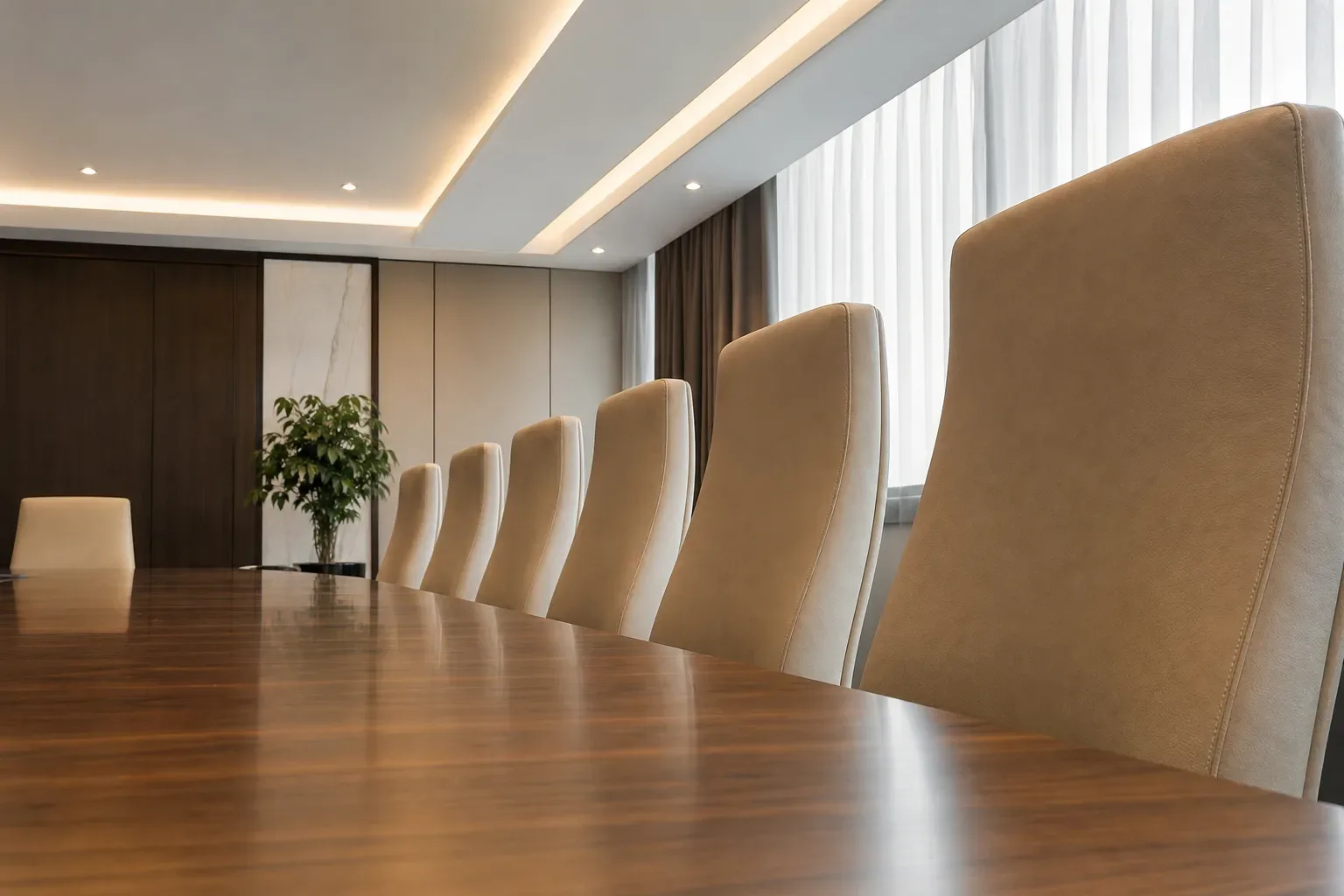A row of high-backed upholstered chairs along one side of a client meeting table, shot from a low angle looking upward in calm even daylight, no person in frame, the chairs evenly spaced and the table surface polished and bare, the room's ceiling visible above the chair backs.