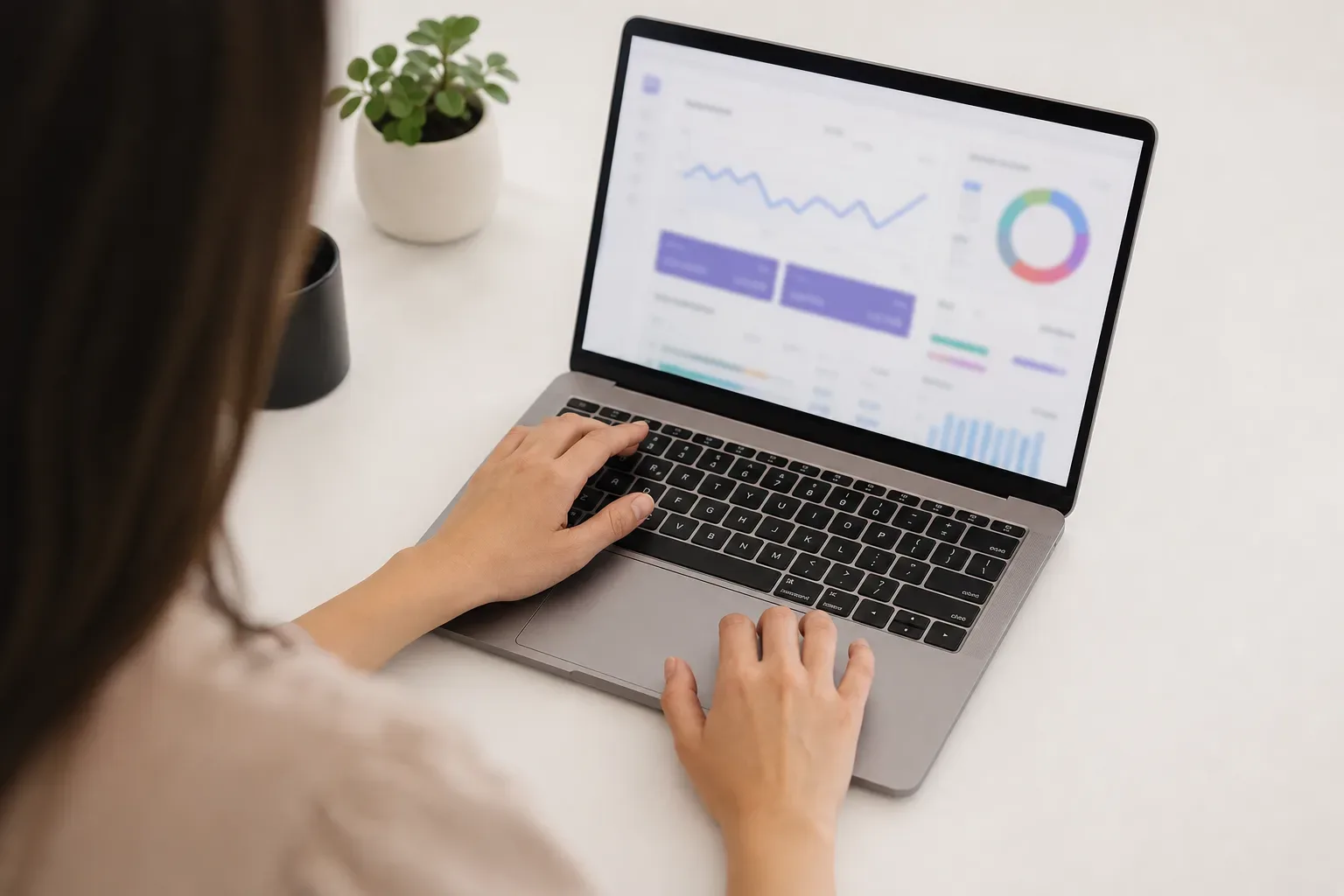 A half-open laptop with a blurred analytics interface glowing on its screen rests on a clear work surface, seen from above in bright flat light, a content specialist's hands partially visible at the keyboard edge, the screen showing abstract cost-per-click panel data.