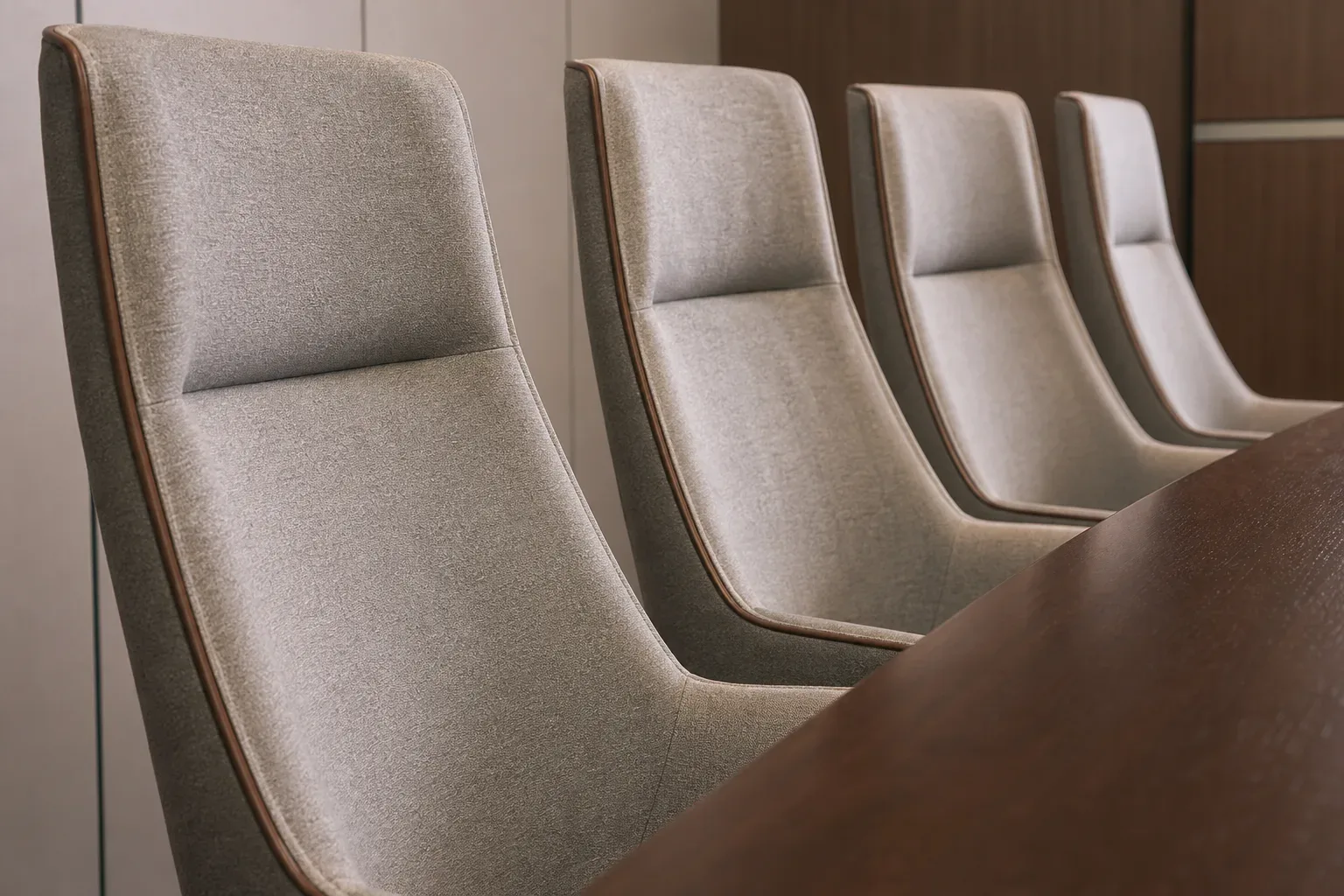 A row of high-backed upholstered chairs along one side of a client meeting table, shot from a low angle looking upward in calm even daylight, no person visible, the chairs and table edge filling the frame.