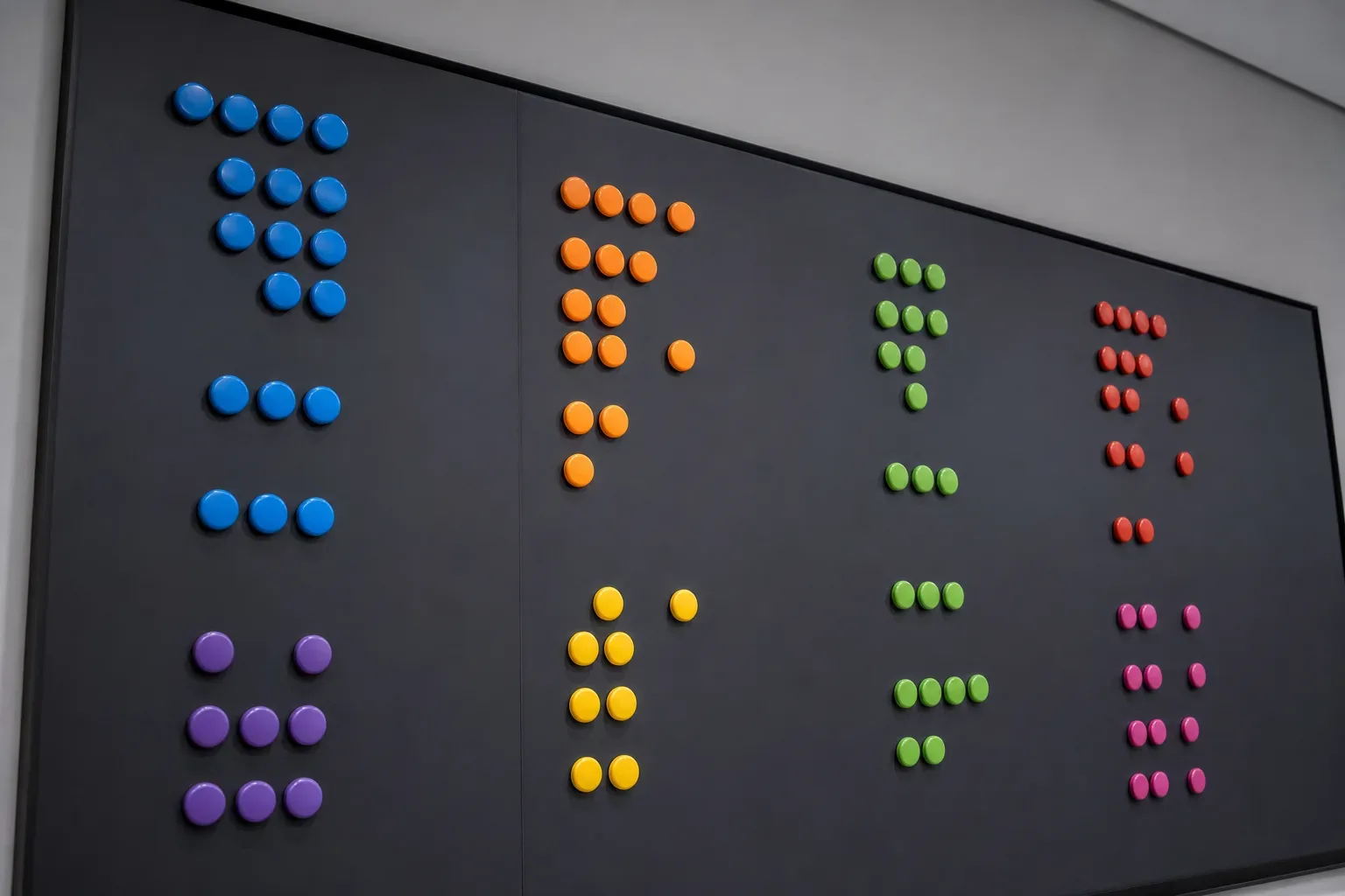 A large wall-mounted planning board with colour-coded magnetic markers arranged in campaign anatomy clusters, shot from a low angle looking upward in calm even daylight, no person visible, the board filling the frame.